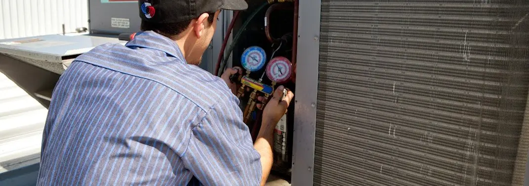 HVAC technician servicing a condenser unit in Pilot Point